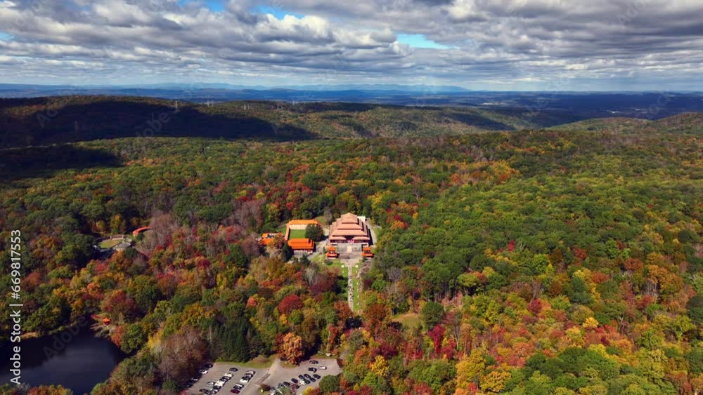 An aerial view of the Chuang Yen Monastery on a sunny day, the leaves of the trees begin to change for autumn. The camera flying high up, dolly in towards the magnificent temple.