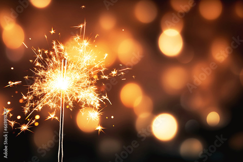 Burning sparkler on festive background with gold bokeh