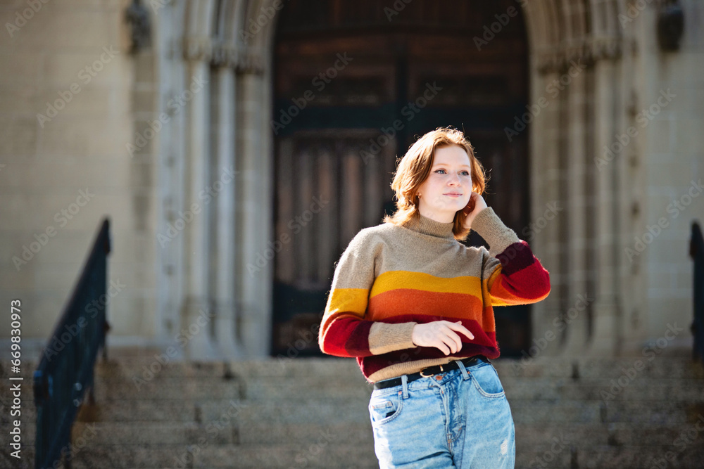 Fototapeta premium Beautiful teen girl standing in front of cathedral steps, backlit.