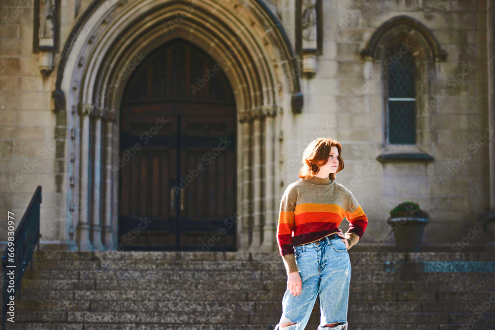 Beautiful teen girl standing in front of cathedral steps, backlit.
