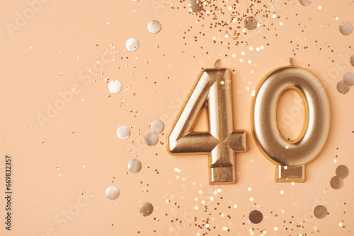 40 years celebration. Greeting banner. Gold candles in the form of number forty on peach background with confetti. photo