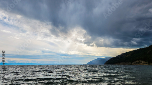 An impending thunderstorm. Clouds over the lake. clouds over the sea. The sun's rays break through the clouds over the lake. Selective focus. © Nikita