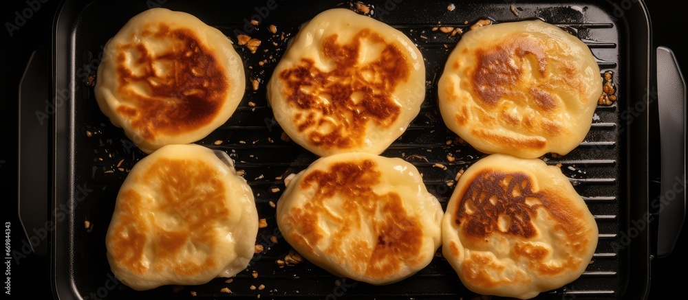 Top view of four pancakes cooking in an electric pan