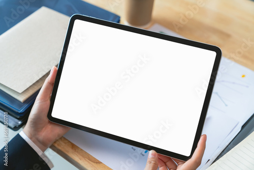 Businessman hand holding digital tablet with blank screen for graphic display montage on the desk in office. photo