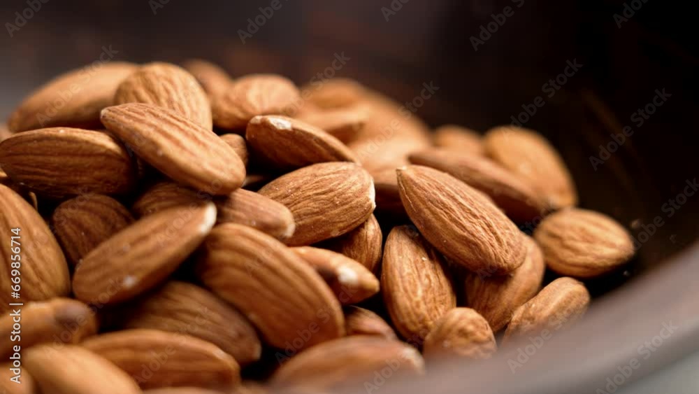 Dried dieting almonds nuts in dark wooden bowl close up. Rotation Dried dieting almonds nuts in dark wooden bowl close up. Rotation