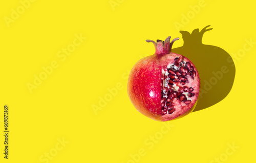 Red pomegranate fruit on light yellow background with copy space. Minimal concept. Creative healthy food idea. Pomegranate aesthetic background. Flat lay composition. Top of view.