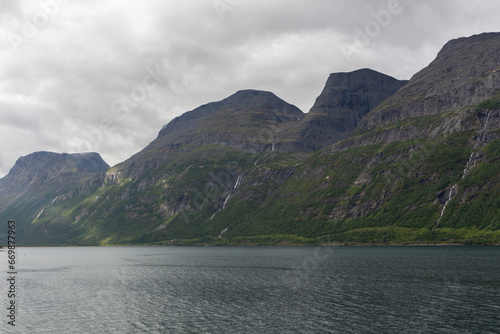 Green mountain slope with waterfalls with lake