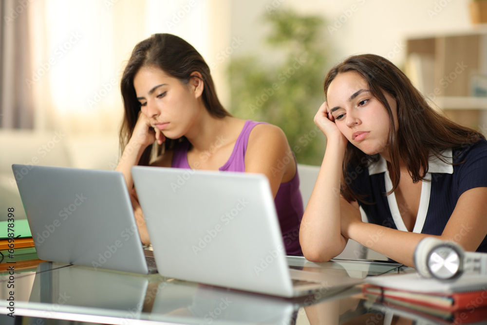 Two bored students waiting online content at home Two bored students waiting online content at home