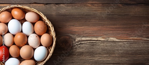 Closeup top view of domestic hens eggs in a basket against an old wooden texture background featuring natural white and red brown eggs