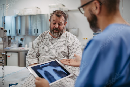 Foto Doctor showing overweight patient chest x-ray, discussing test result in emergency room