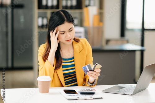 Asian business woman is stressed, bored, and overthinking from working on a tablet at the office.