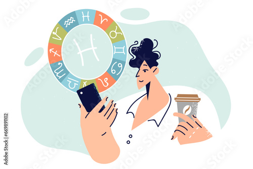 Man reads horoscope on mobile phone and holds cup coffee in hands standing near zodiac sign pisces