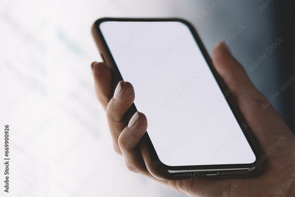 Close up view of hand holding modern smartphone with big blank screen for content template
