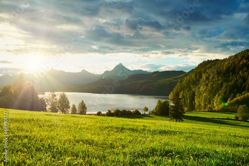 Beautiful Bavarian landscape with a meadow, mountains and a lake, sunrise, partly cloudy