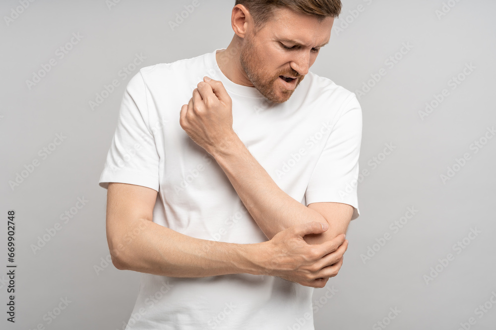 Man touching hand elbow feeling pain isolated on gray background after