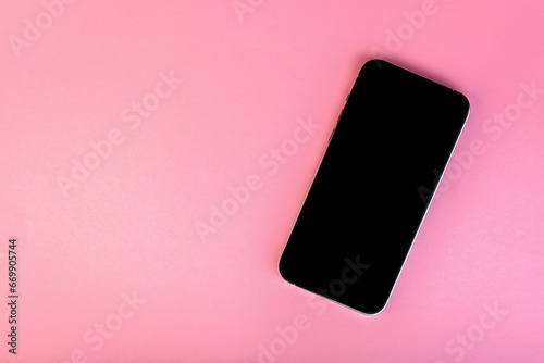Smartphone with black screen on pink background with copy space.