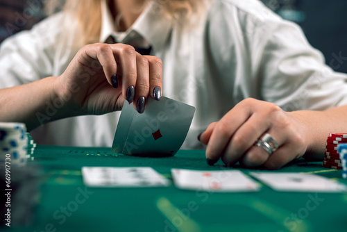 attractive girl in shirt and hat covering face with hat holding poker cards in casino. poker photo