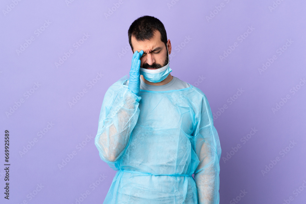 Surgeon man with beard with blue uniform over isolated purple background with headache Surgeon man with beard with blue uniform over isolated purple background with headache