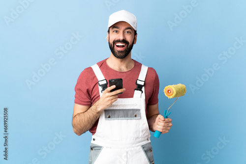 Adult painter man over isolated blue background surprised and sending a message