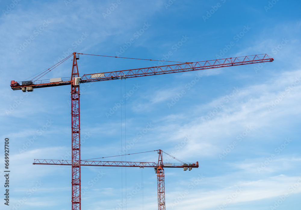 Construction cranes on blue cloudy sky background Construction cranes on blue cloudy sky background