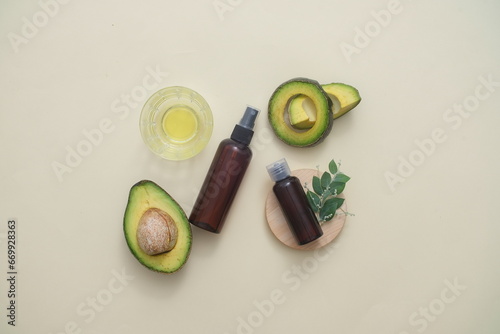 Flat lay of a bottle without label displayed with fresh avocado. Branding mockup. Avocado (Persea americana) is a great source of biotin, help prevent brittle hair and nails. Beauty from nature.