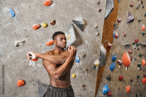 handsome athletic african american man with his shirt off stretching his arms and looking away