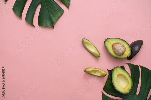 Vászonkép Fresh avocado with green leaves on pink background