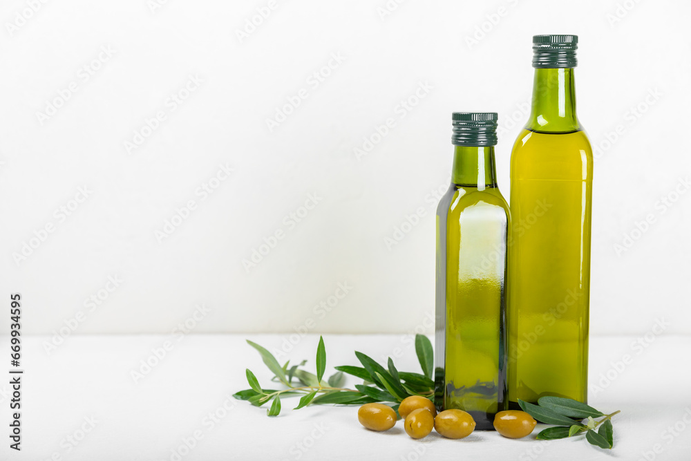 Olive oil in a bottle on texture background. Oil bottle and a bowl with branches and fruits of olives. Place for text. copy space. cooking oil and salad dressing. Olive oil in a bottle on texture background. Oil bottle and a bowl with branches and fruits of olives. Place for text. copy space. cooking oil and salad dressing.