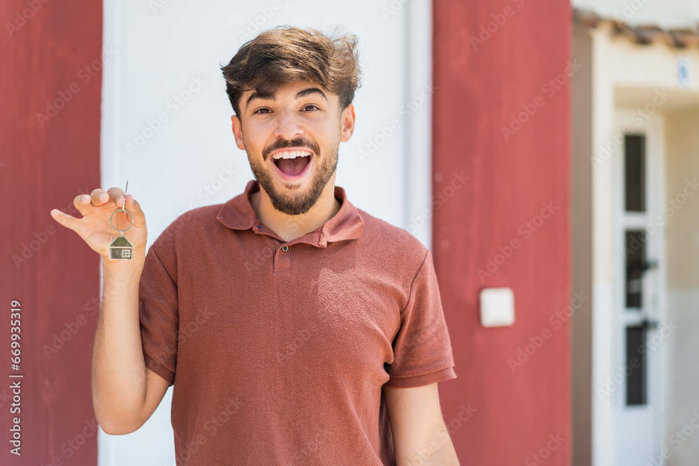 © luismolinero - Young Arabian handsome man holding home keys at outdoors with surprise and shocked facial expression