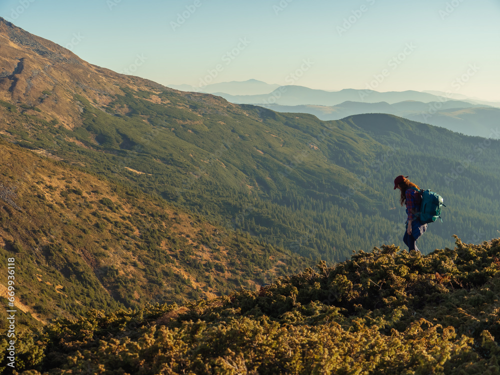 Descent of hiker tourist woman with backpack during mountain trekking from the top.