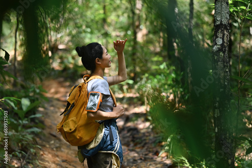 Active female hiker with backpack trekking in forest, exploring nature. Traveling, trekking and adventure concept.