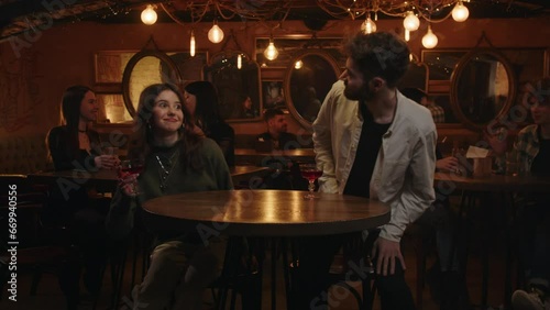 A young couple. On a date in vintage restaurant. Two friends mets at local bar drinking cocktails and speaking about life. Happy relaxing boyfriend with girlfriend talking while drinks negroni