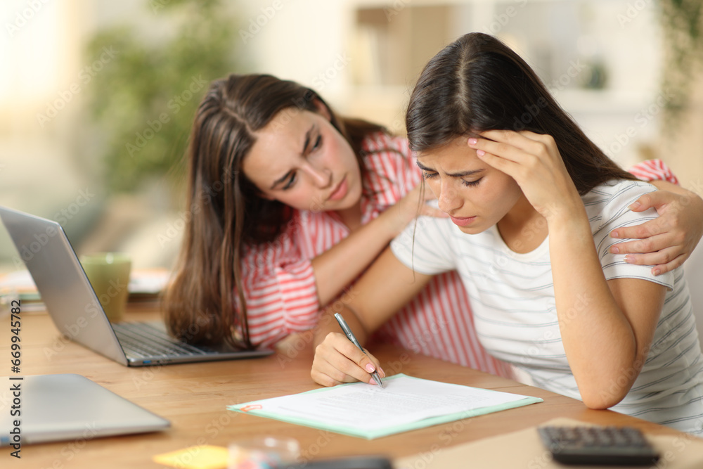 Worker comforting a sad colleague signing contract Worker comforting a sad colleague signing contract
