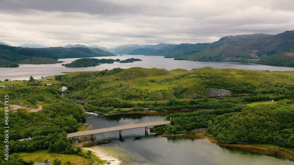 Scotland. Drone Shot Of Jacobite Steam Train Crossing Morar Railway Viaduct In Beautiful Coastal Mountain Landscape Of Scottish Highlands, Scotland, United Kingdom. Loch Morar, West Coast Of Scotland. Scotland. Drone Shot Of Jacobite Steam Train Crossing Morar Railway Viaduct In Beautiful Coastal Mountain Landscape Of Scottish Highlands, Scotland, United Kingdom. Loch Morar, West Coast Of Scotland.