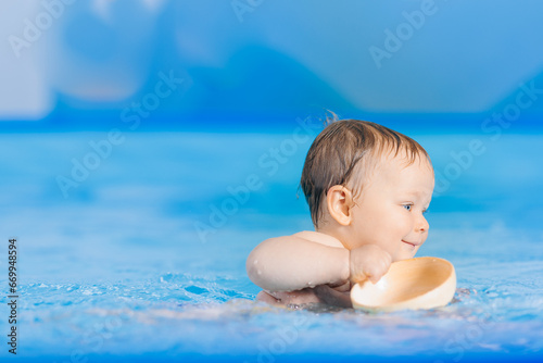 Portrait happy baby girl play with toy in swimming pool, teaching small swimmer. Concept healthcare sport for infant