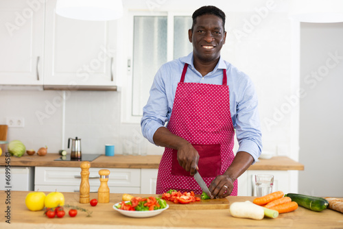  Man in an apron is standing at his desk at home