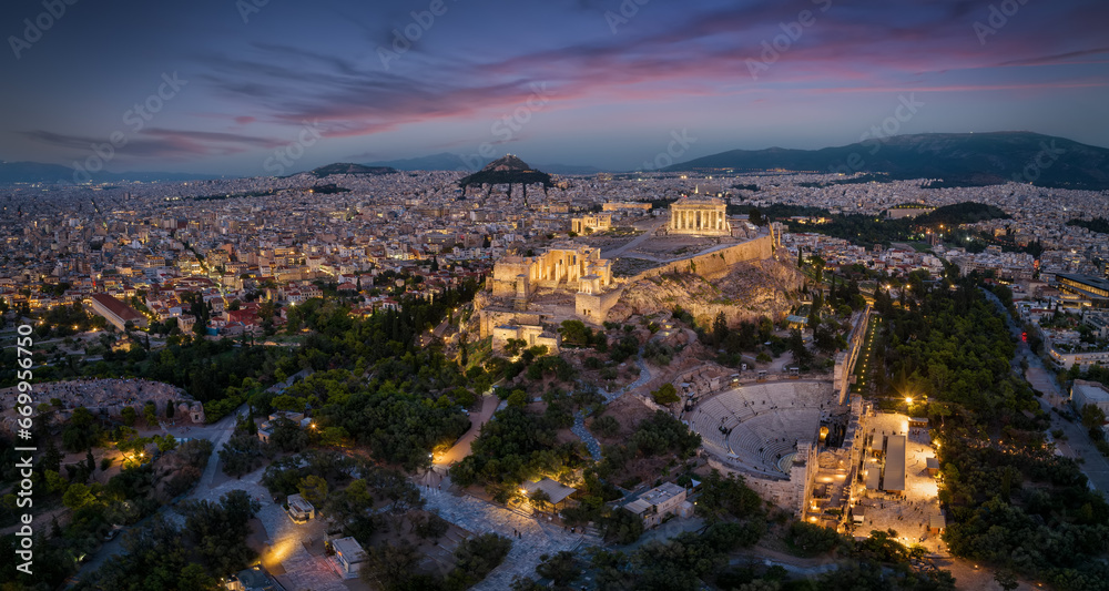 Fototapeta premium Aerial view of the illuminated skyline and ancient ruins at the Acropolis of Athens, Greece, with Parthenon Temple and Odeon of Herode theatre during evening