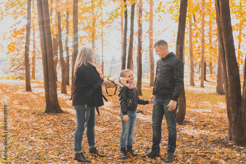 Family spend time in autumn park with a dog. Father, mother and daughter and jack russell terrier dog having fun in fall Family spend time in autumn park with a dog. Father, mother and daughter and jack russell terrier dog having fun in fall