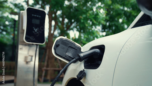 Closeup progressive modern transportation concept, electric car being charged at charging station with high detail of reflection from sky. Eco-friendly electric vehicle driven by renewable energy.