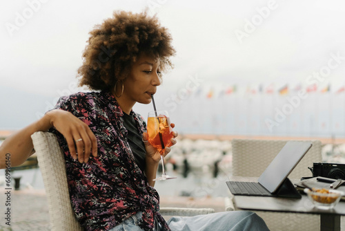 Young woman drinking and using tablet PC at table photo