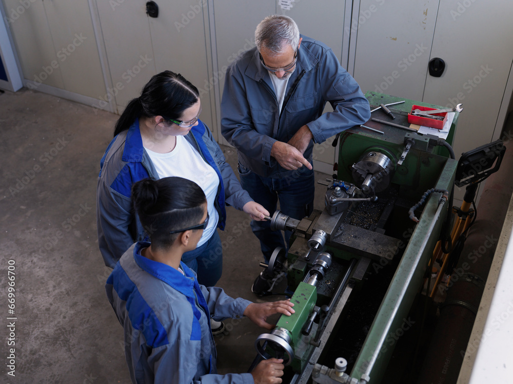 Instructor explaining lathe machine to trainees at workshop