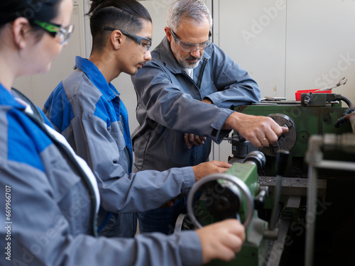 Instructor giving lathe machine training to trainees at workshop photo