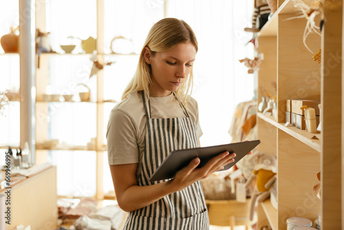 Owner wearing apron taking inventory on tablet PC at store