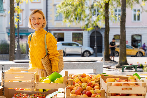 Smiling woman wearing sweater doing shopping at farmer's market photo