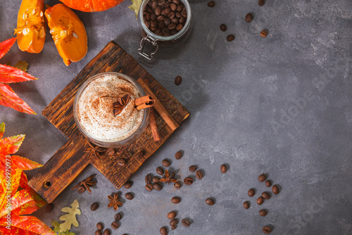 A glass of autumn pumpkin latte with whipped cream and spices. Coffee with pumpkin and cinnamon on a gray background, top view copy space
