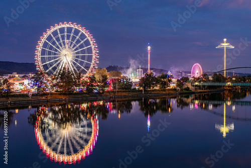 Germany, Baden-Wurttemberg, Stuttgart, Cannstatter Wasen, Glowing Ferris Wheel reflecting in Neckar river at night photo