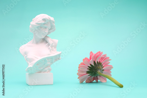 Female bust sculpure greek style with gerbera flower on blue background