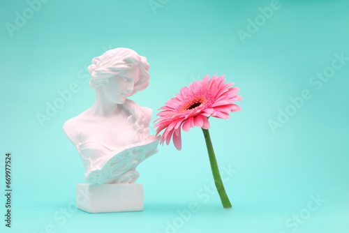 Female bust sculpure greek style with gerbera flower on blue background