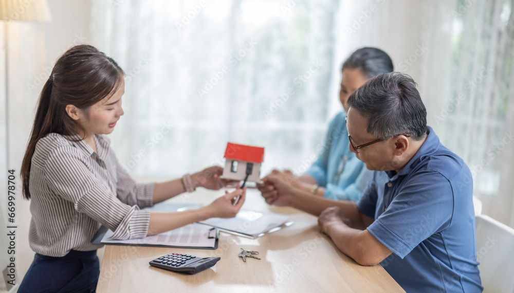 Elderly couples satisfying retirement home purchase with contract and key handover from a saleswoman