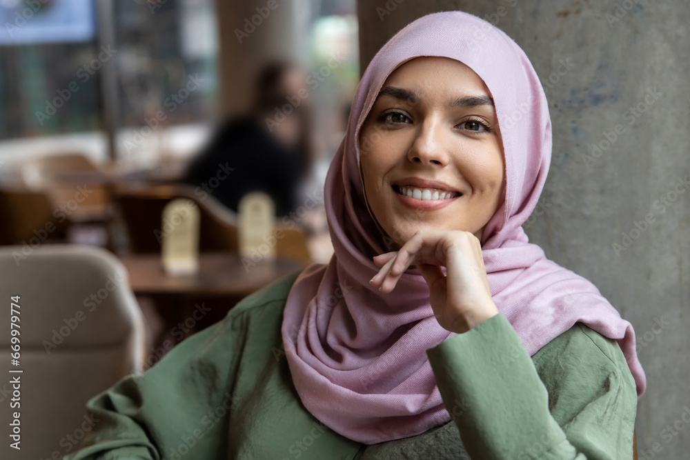 Cute woman in hijab sitting in a cafe and smiling Cute woman in hijab sitting in a cafe and smiling